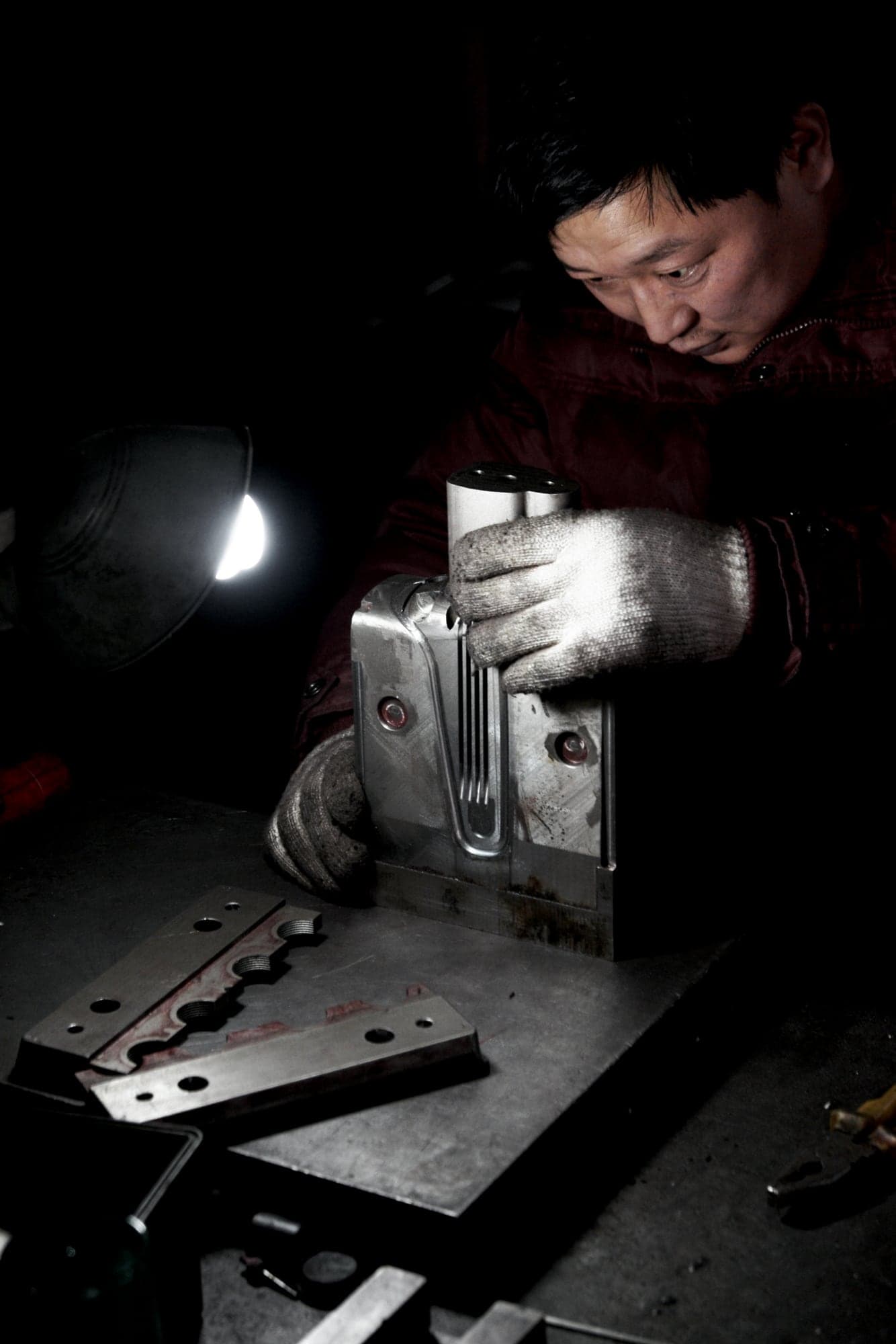 A worker inspecting a metal mould in the dark