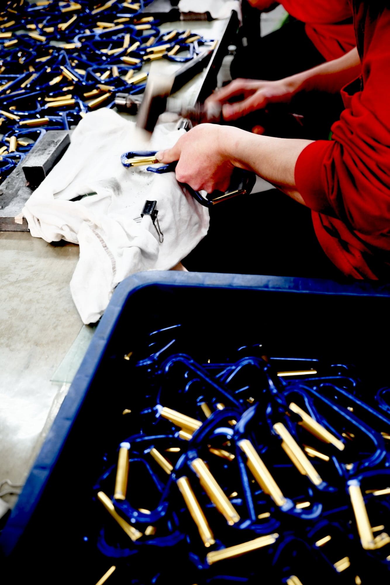 A worker sorting blue carabiners at a bench