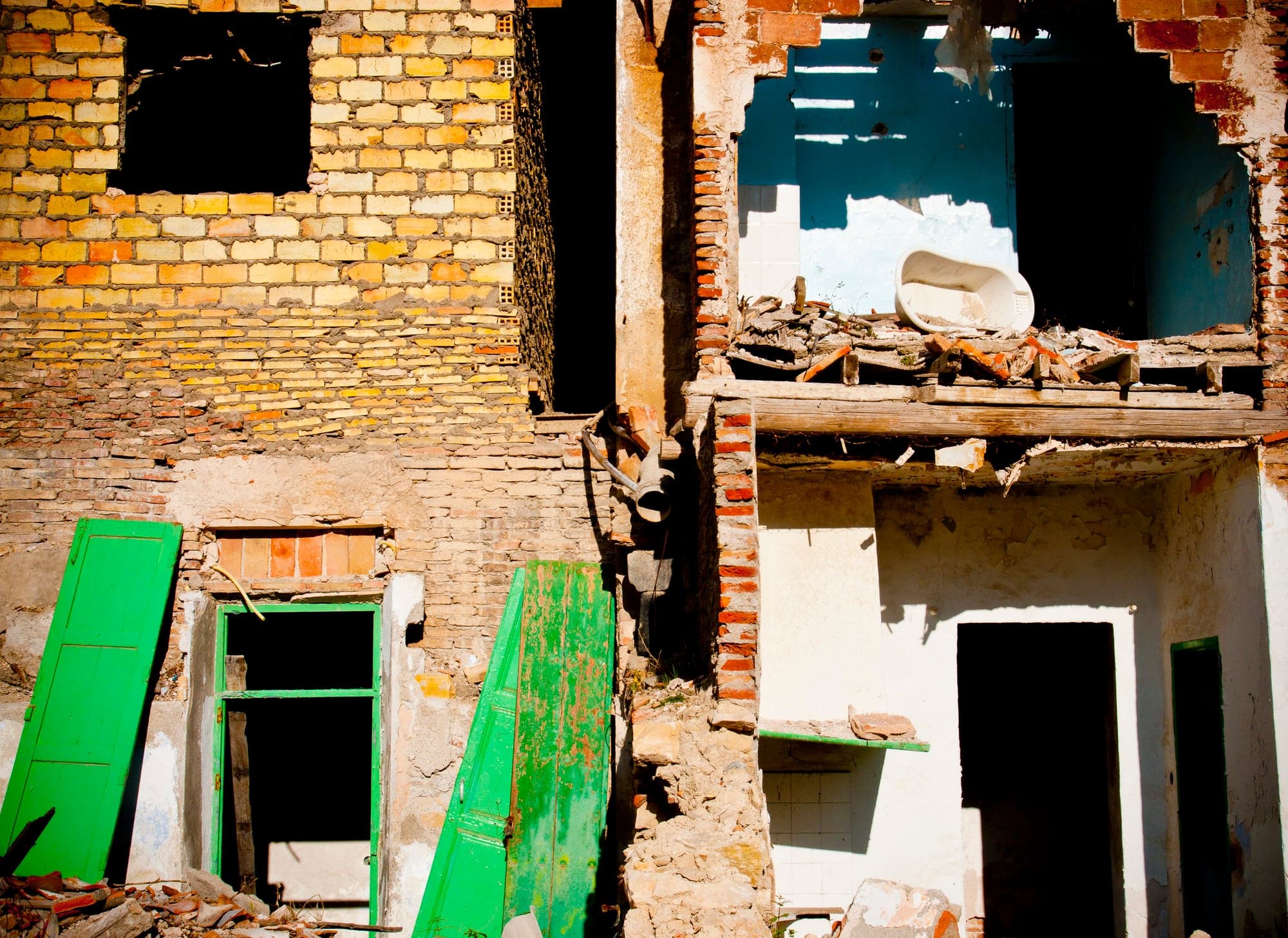 A ruined brick house with green shutters