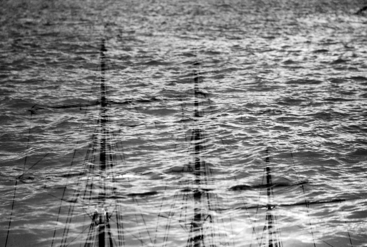 Schiffsmasten doppelt über bewegtem Wasser
