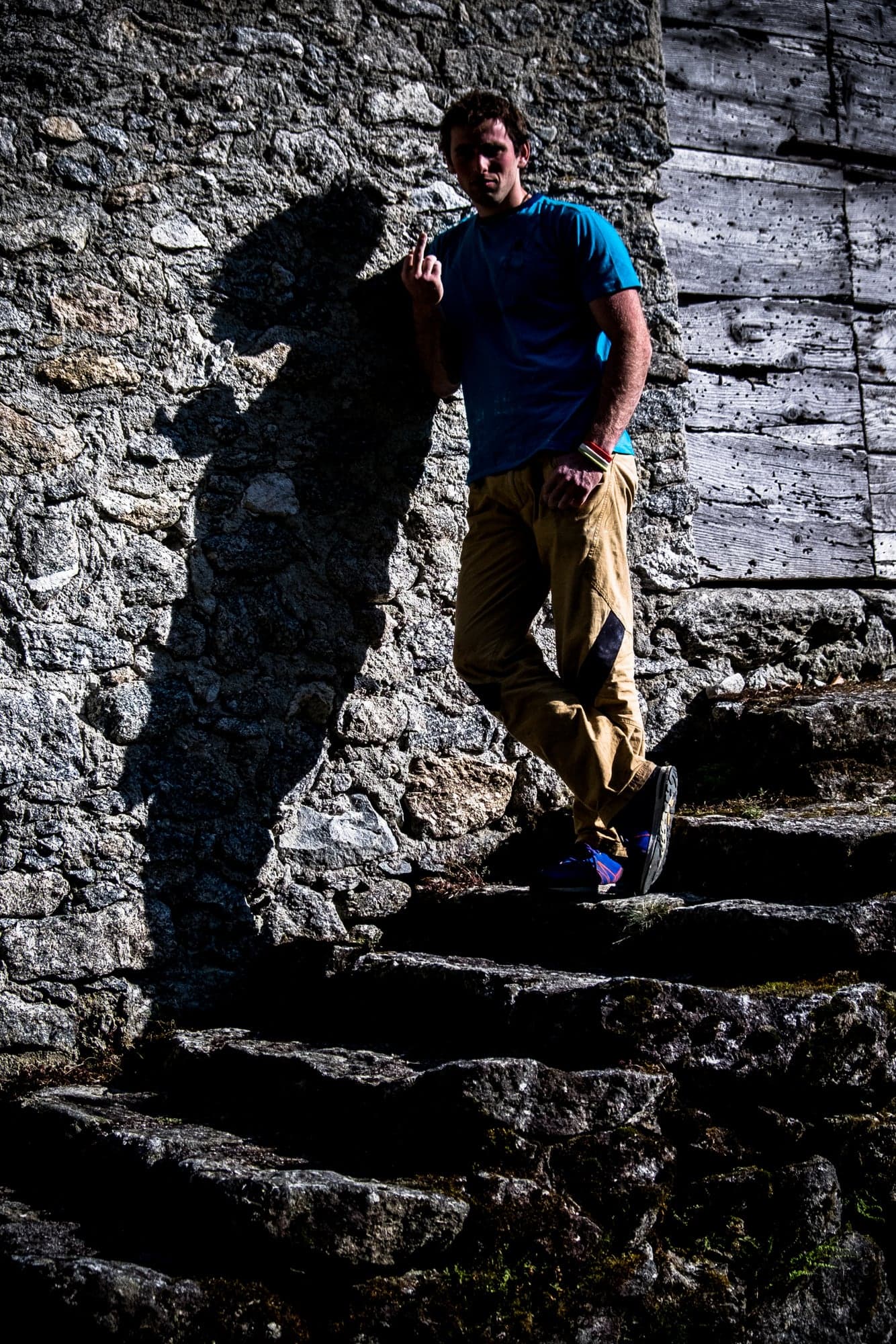 A man leaning on stone stairs, a long shadow beside him
