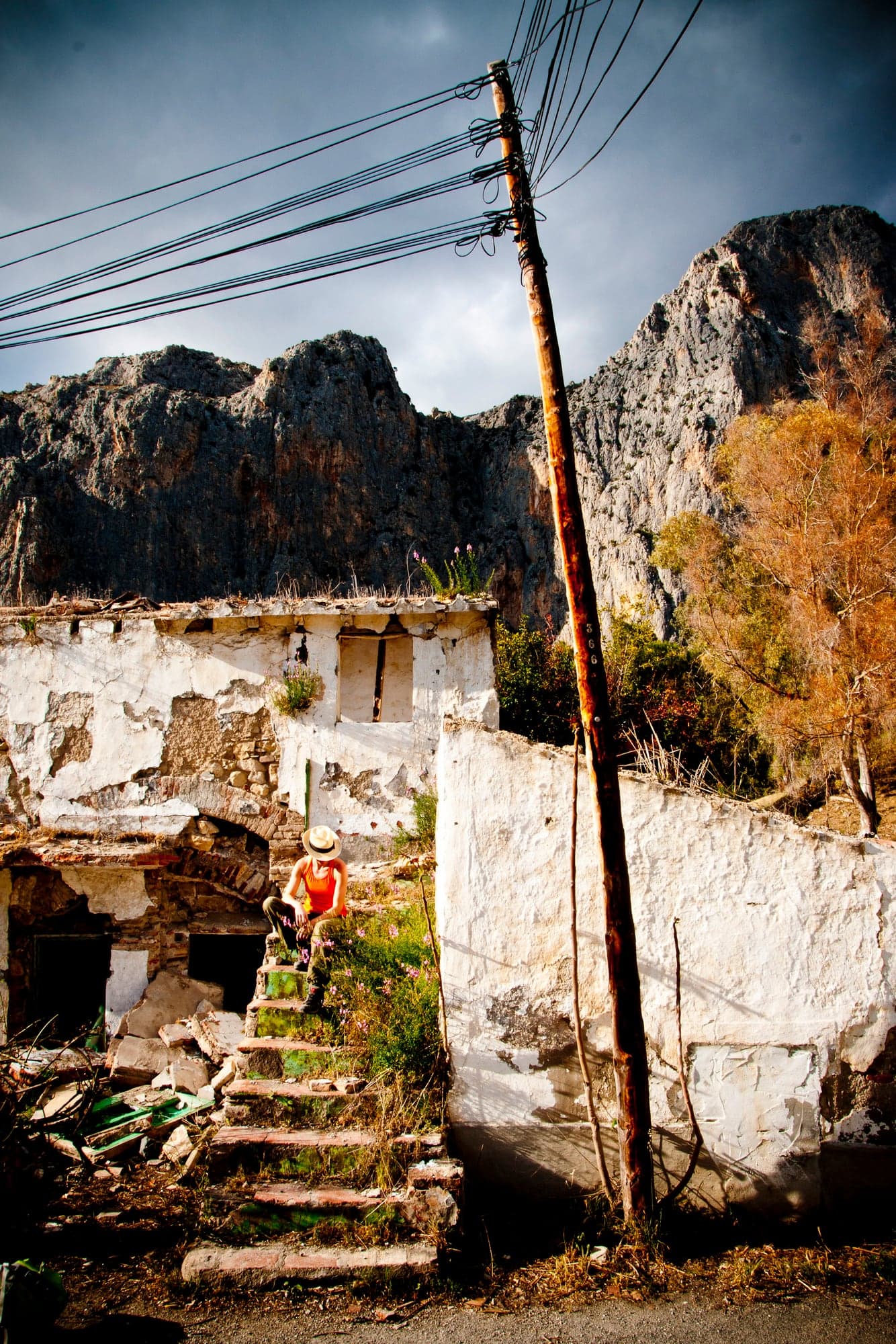 A power pole standing over ruined stone houses