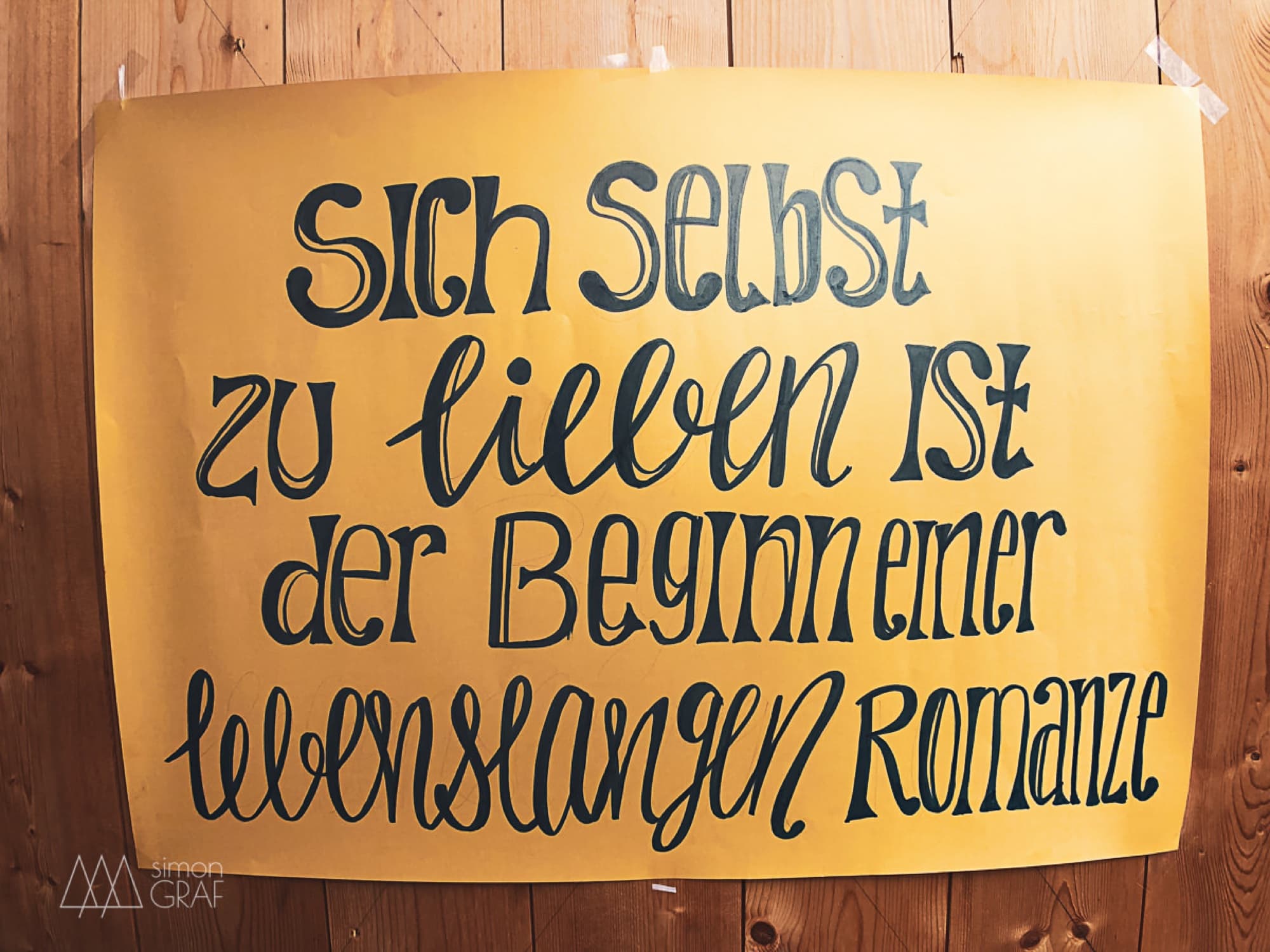 A hand-lettered sign: loving yourself is the beginning of a lifelong romance