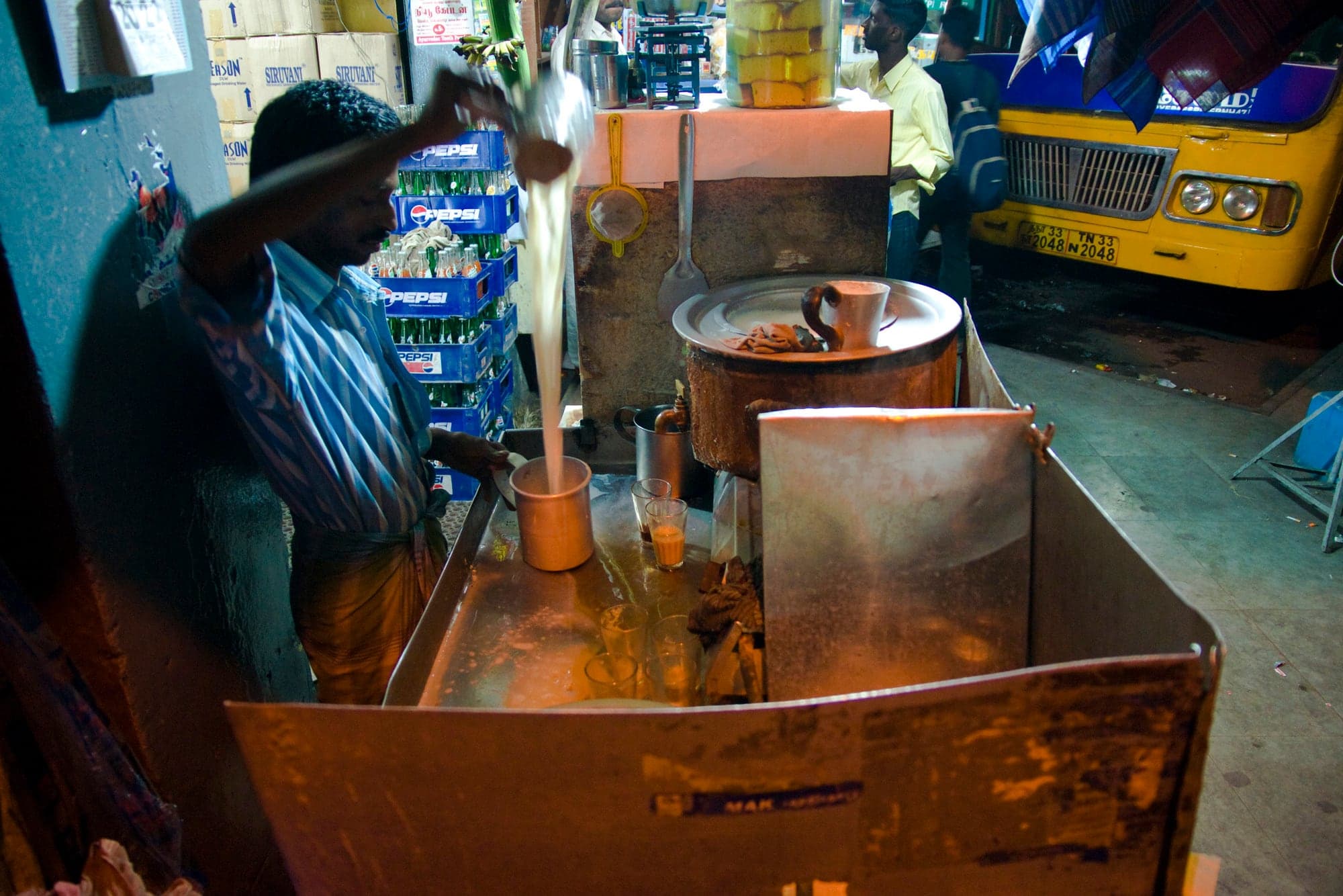 A man cooking at a blue-lit street stall