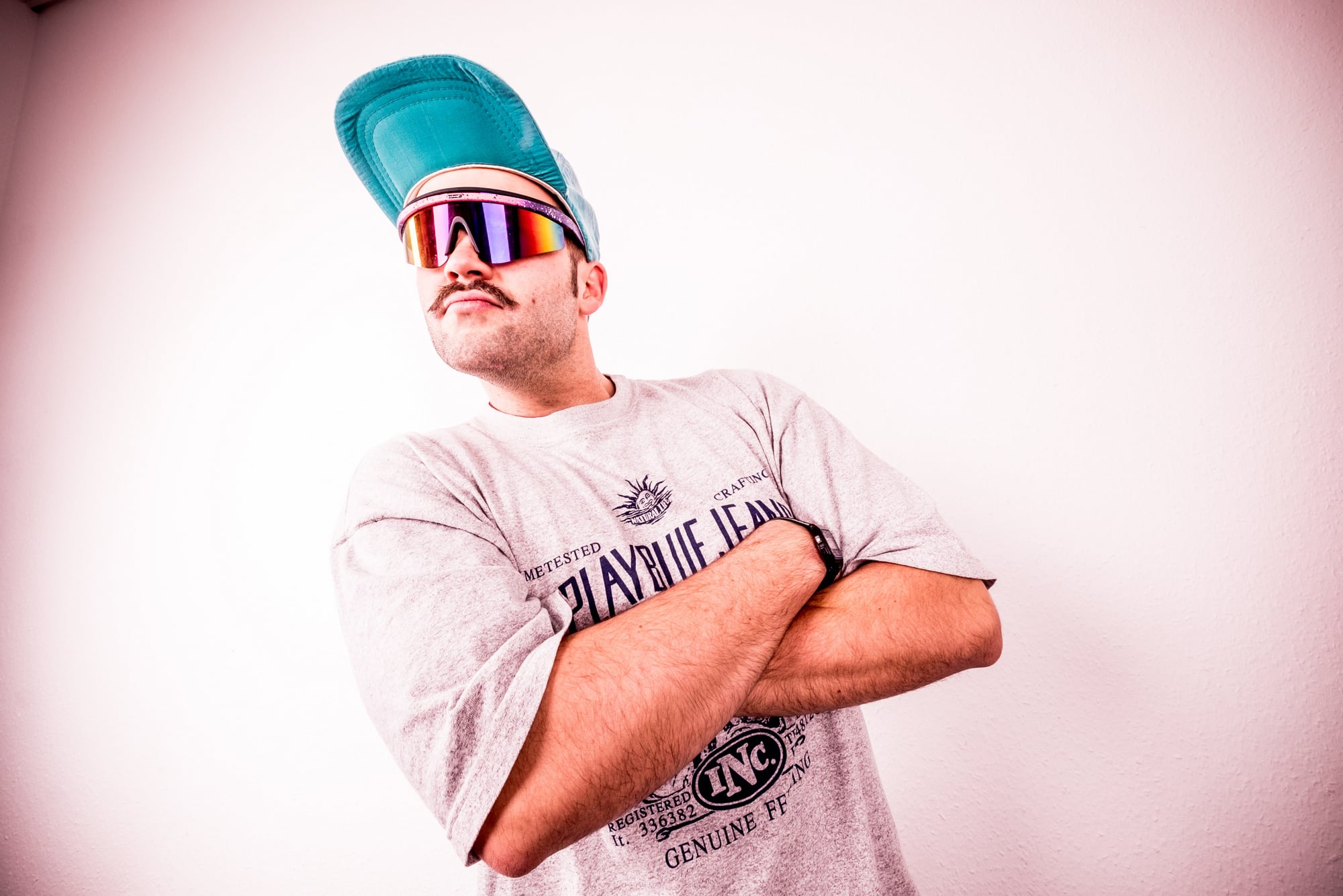 Ein junger Mann mit Cap und Sonnenbrille, verschränkte Arme