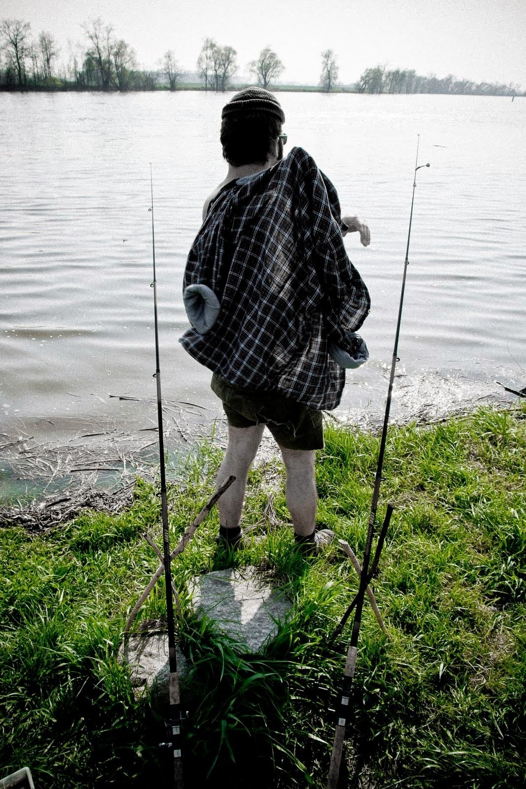 Ein Angler am See, mit dem Rücken zur Kamera