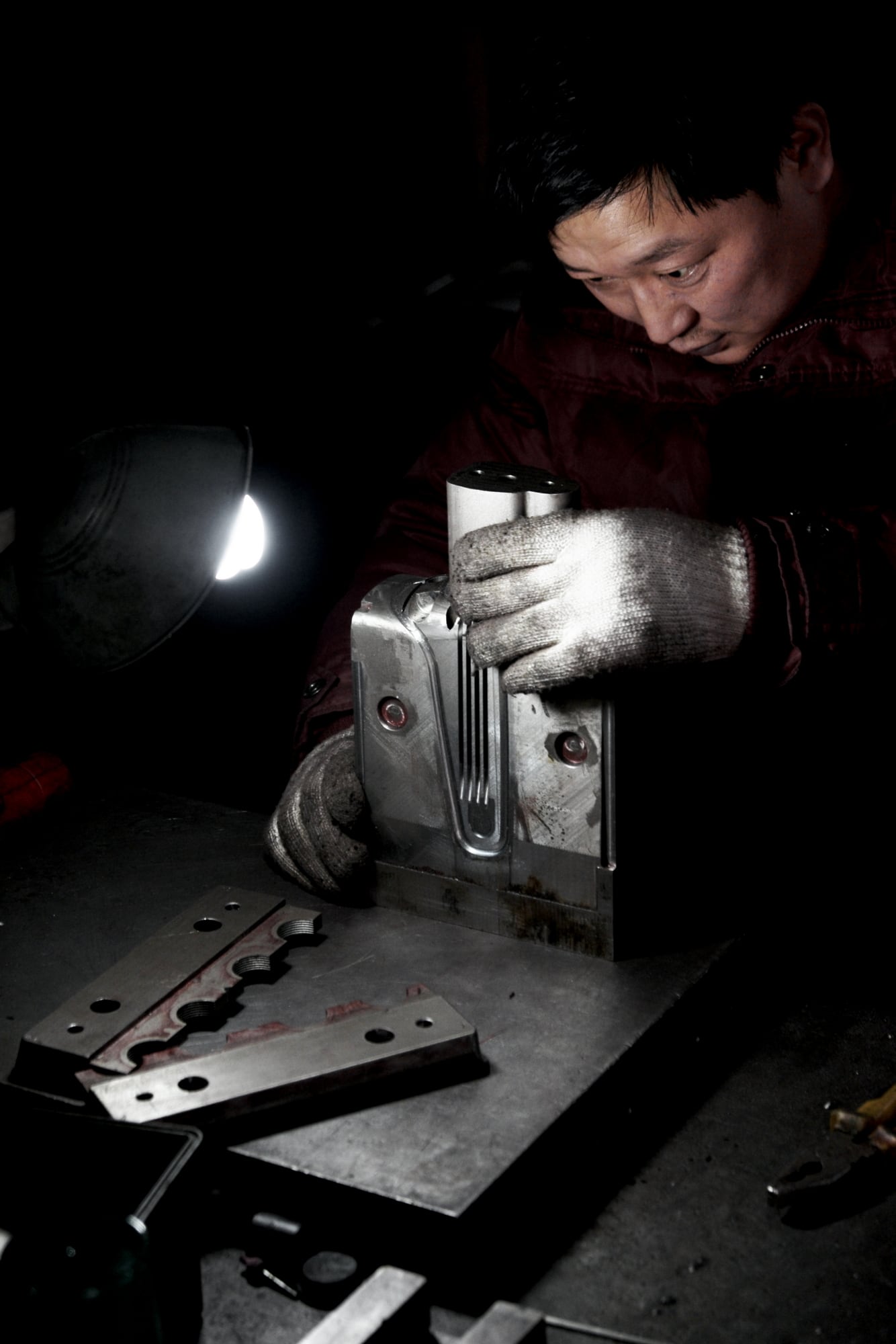 Ein Arbeiter prüft eine Metallform im Dunkeln