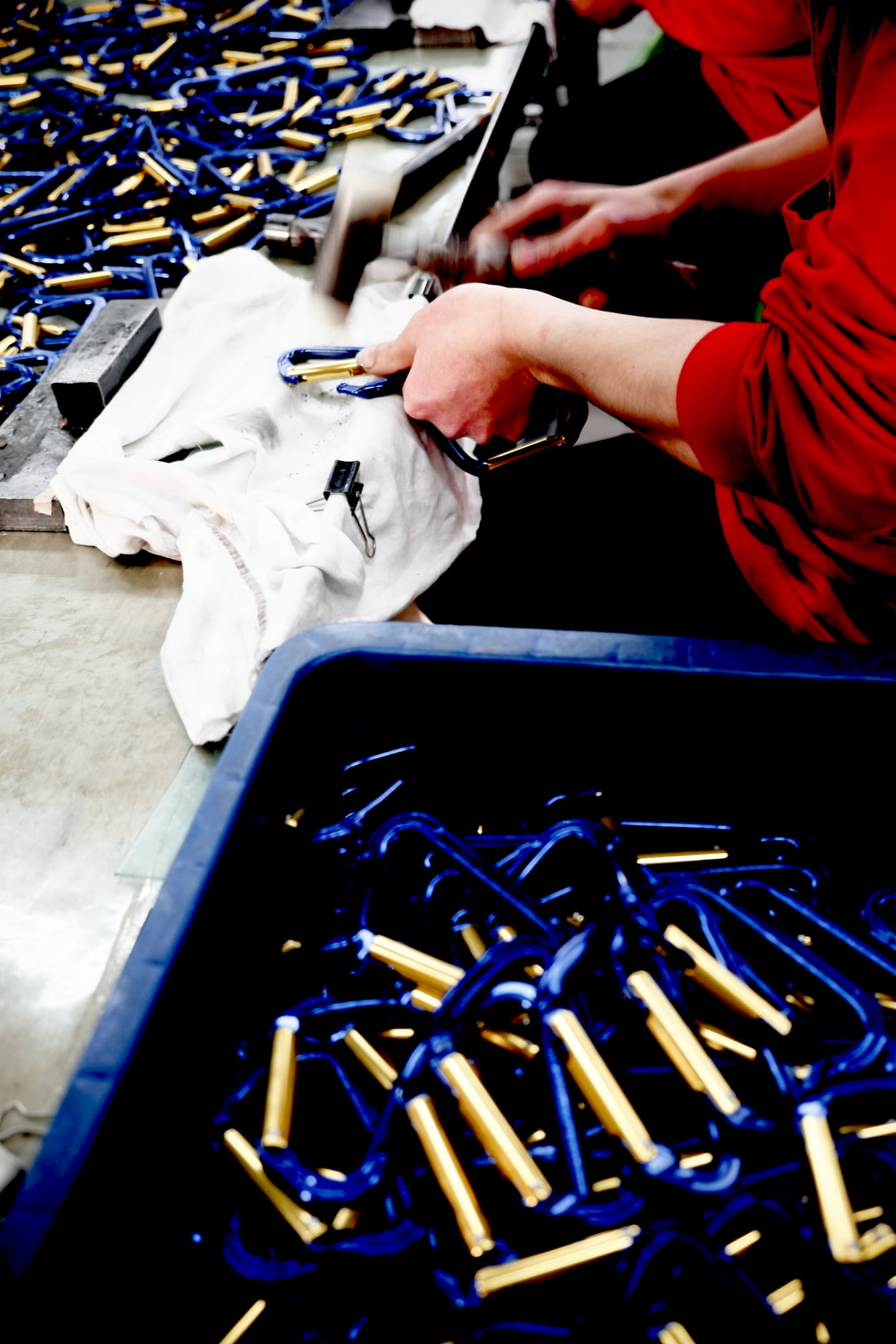 Ein Arbeiter sortiert blaue Karabiner an der Werkbank