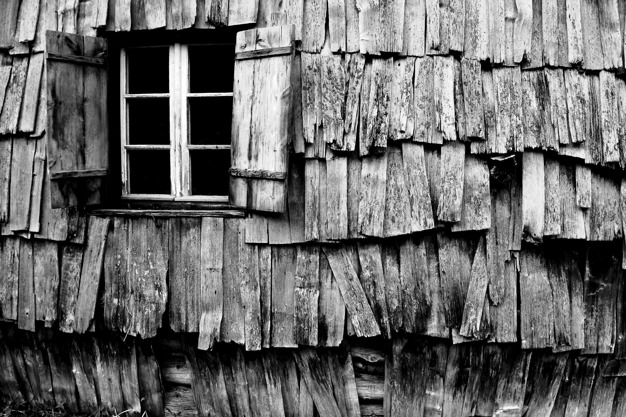 Eine verwitterte Schindelwand und ein Fenster