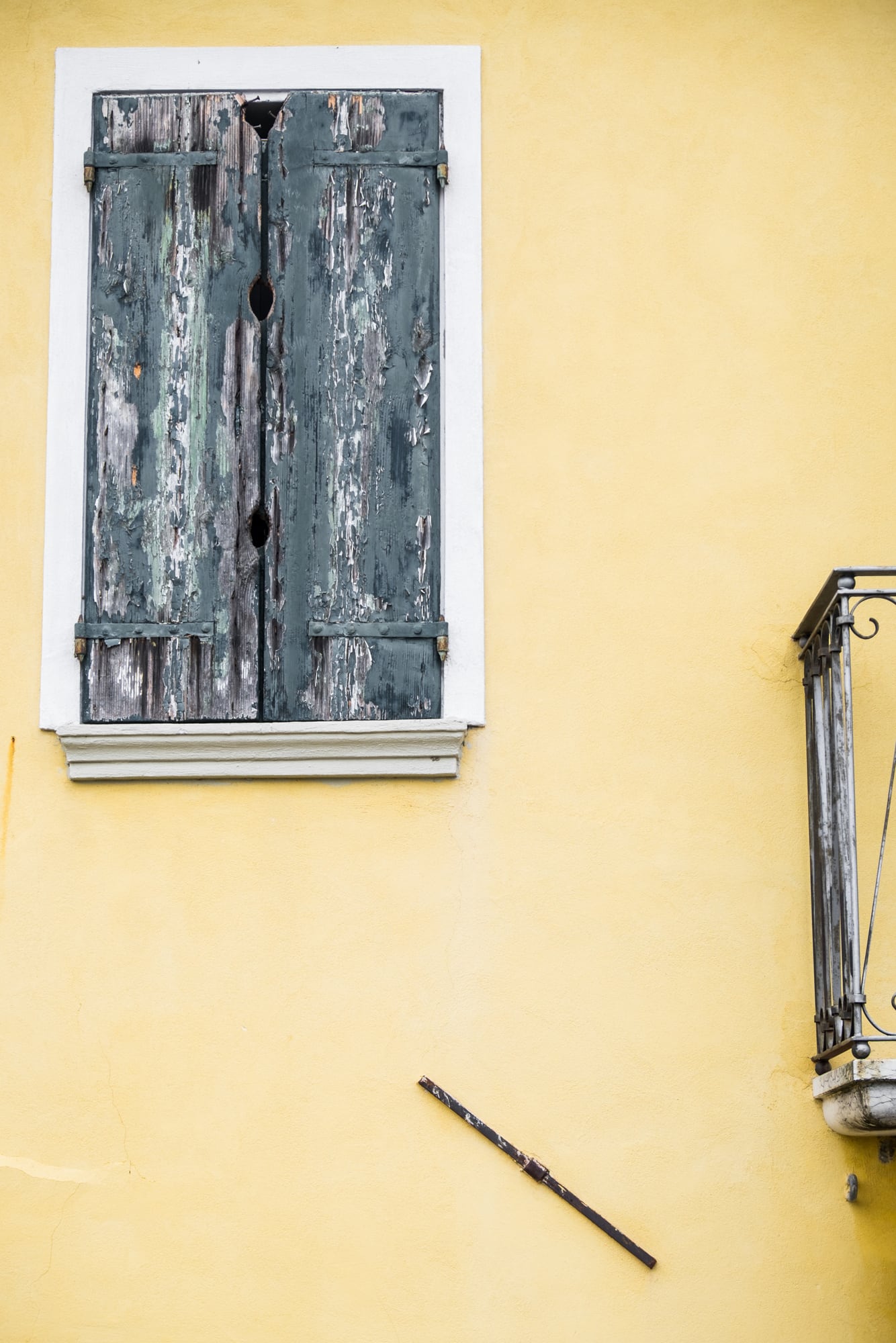 Graue Fensterläden an einer gelben Wand