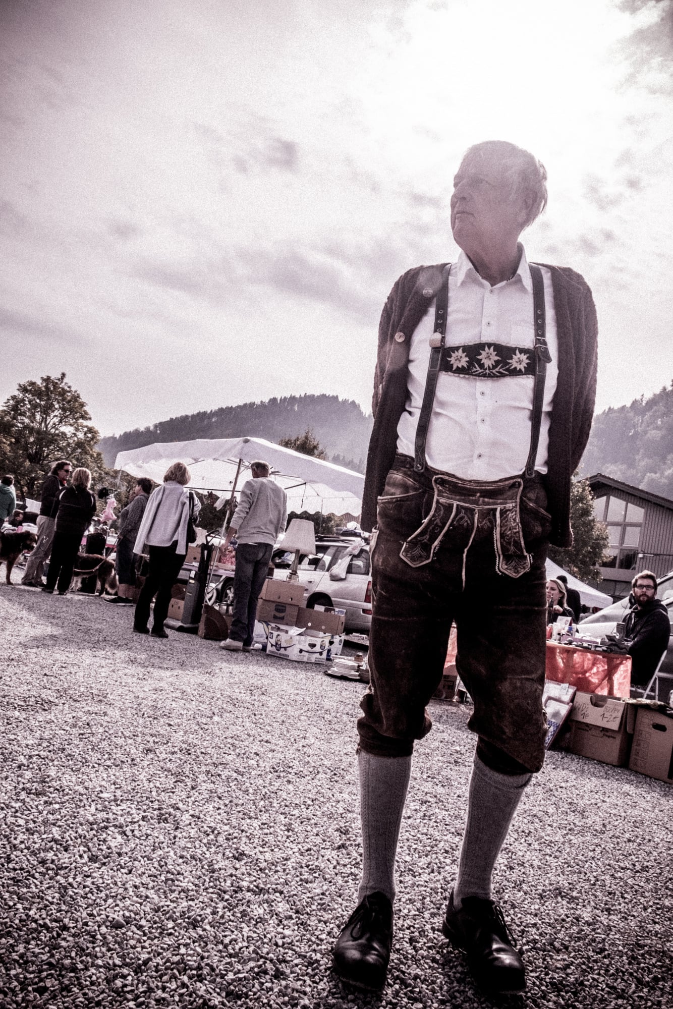 Ein Mann in Lederhosen auf einem Flohmarkt, in Schwarz-Weiß