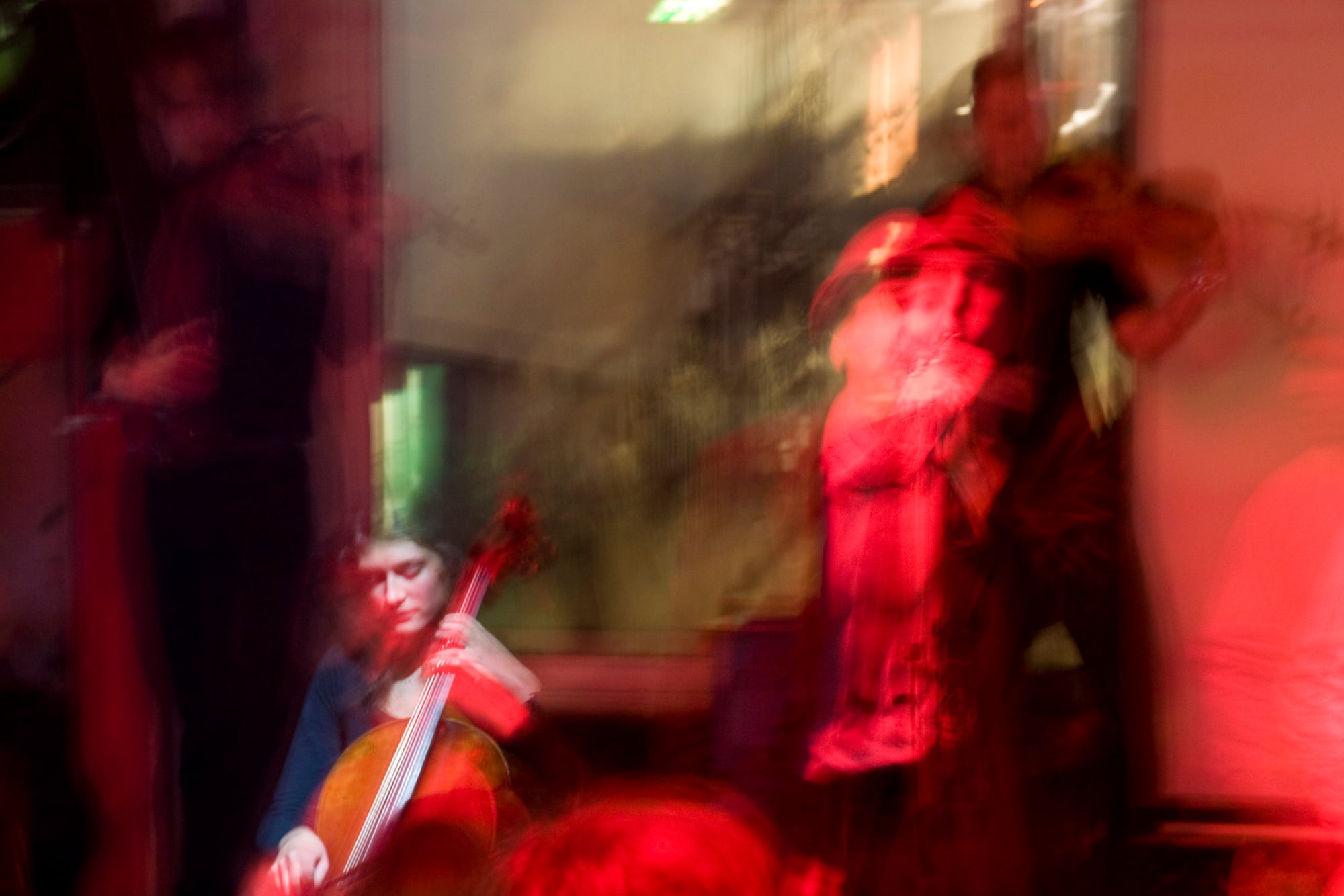 Cello und Gestalten im roten Licht